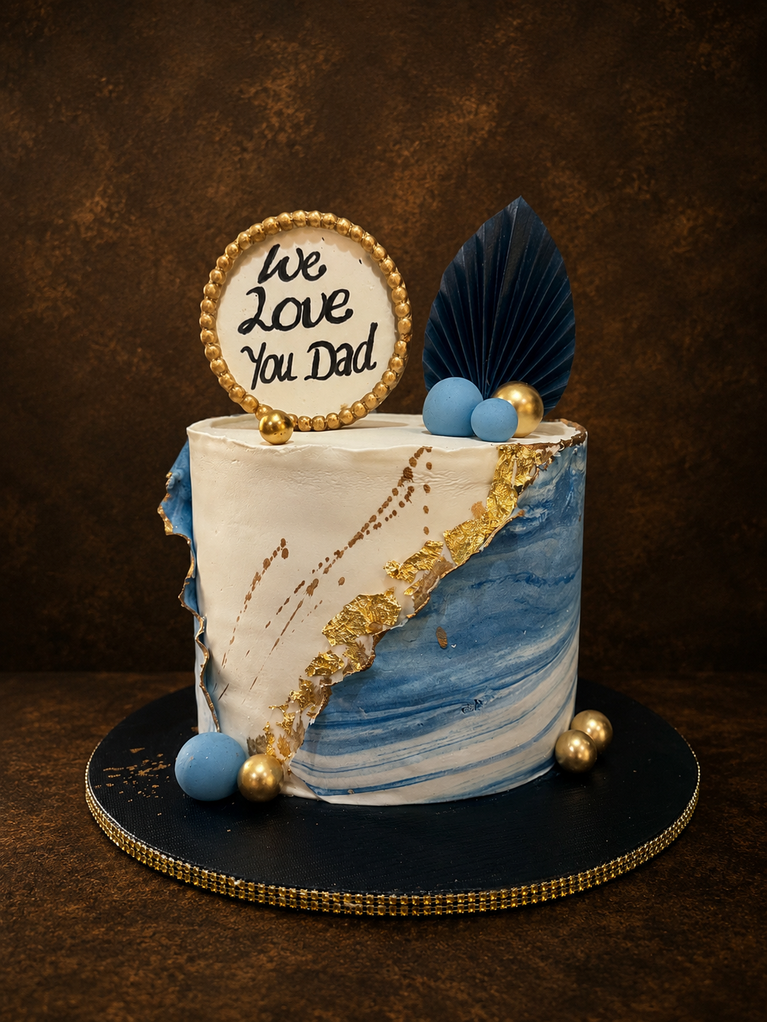 Blue and white marble buttercream cake with gold leaf accent and navy fan topper by Cakes by Teez in Abuja