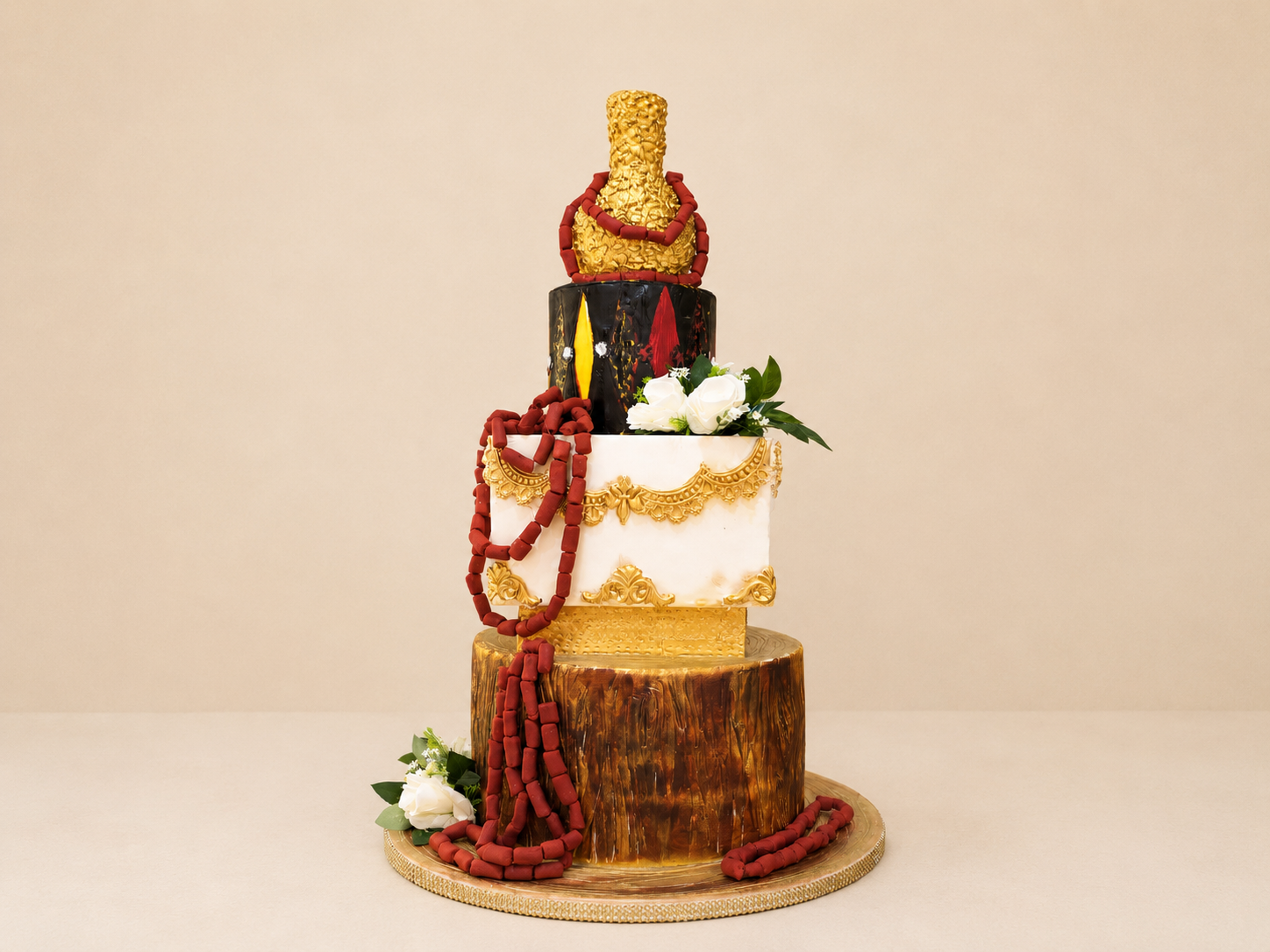 Nigerian traditional three-tier wedding ceremony cake with coral beads, gold detailing, and floral accents by Cakes by Teez in Abuja