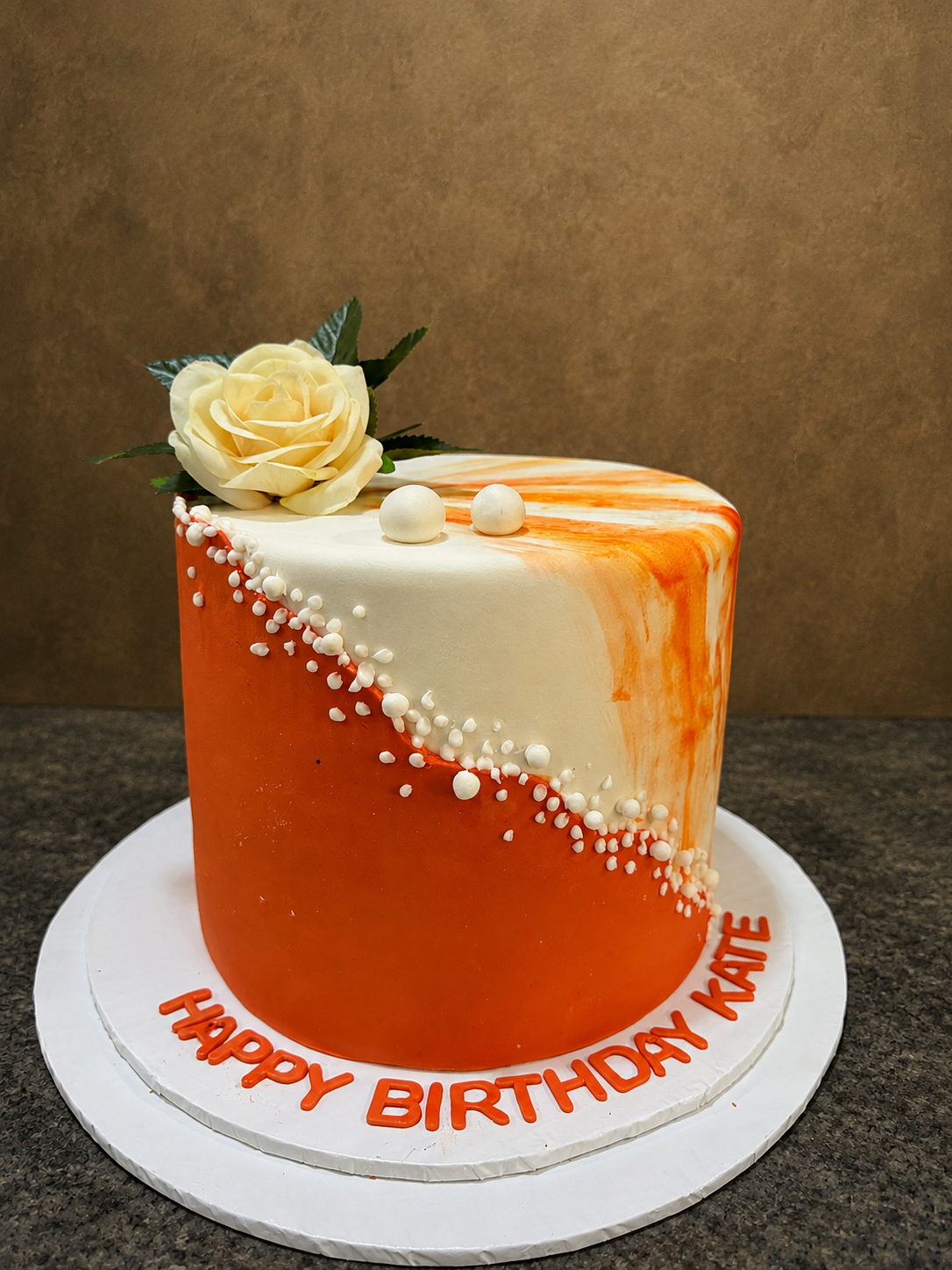 Orange and white marble buttercream birthday cake with cream rose and cascading sugar pearls by Cakes by Teez in Abuja