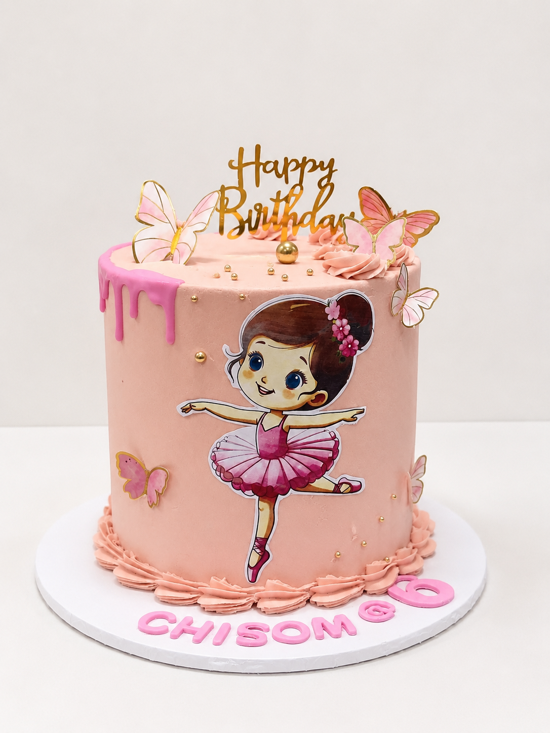 Pink buttercream birthday cake with ballerina character print and gold butterfly toppers by Cakes by Teez in Abuja