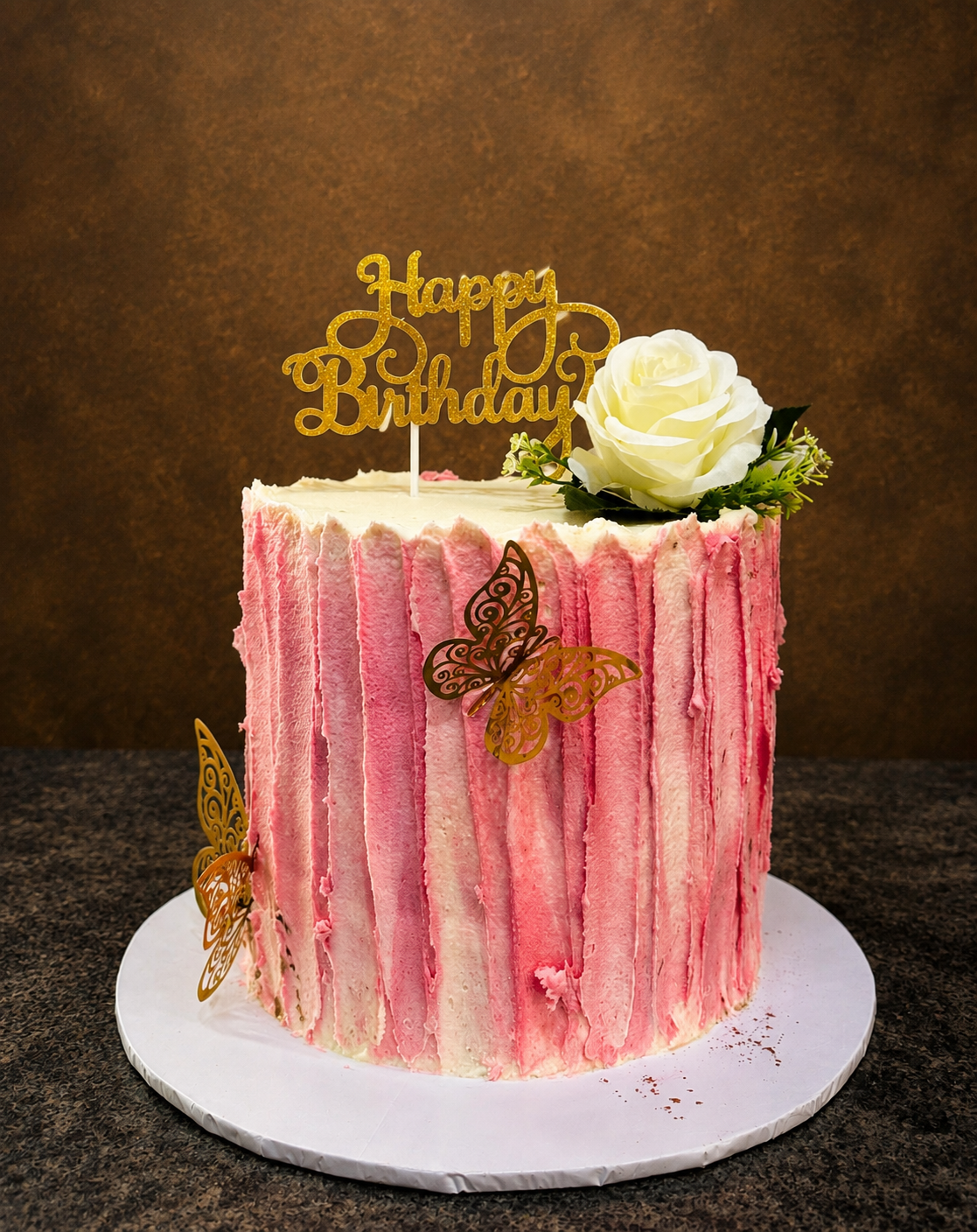 Pink ombre textured buttercream birthday cake with white rose and gold butterfly toppers by Cakes by Teez in Abuja