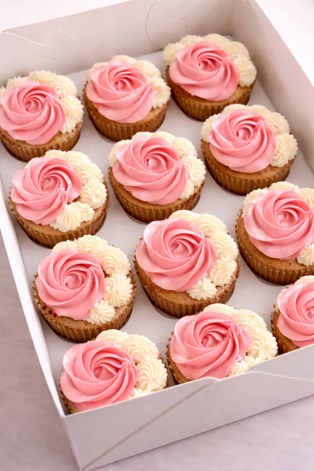 Cupcakes Box of twelve soft cupcakes with pink and white buttercream rose swirl piping by Cakes by Teez in Abuja