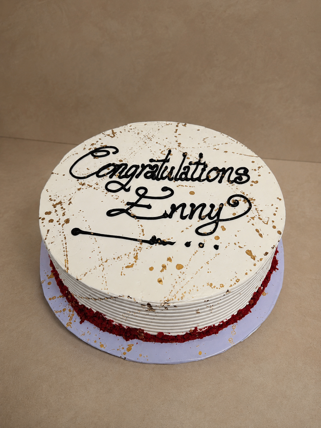 White buttercream cake with gold paint splatter and red velvet crumble border by Cakes by Teez in Abuja